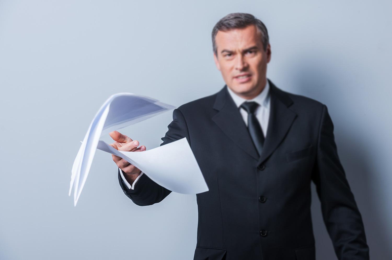 A frustrated businessman throwing documents toward the viewer